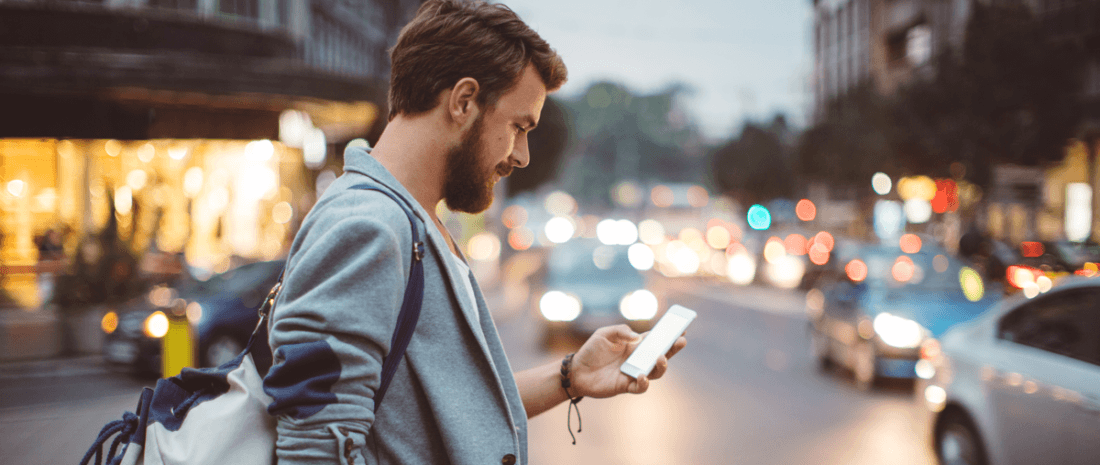 man looking at phone in city